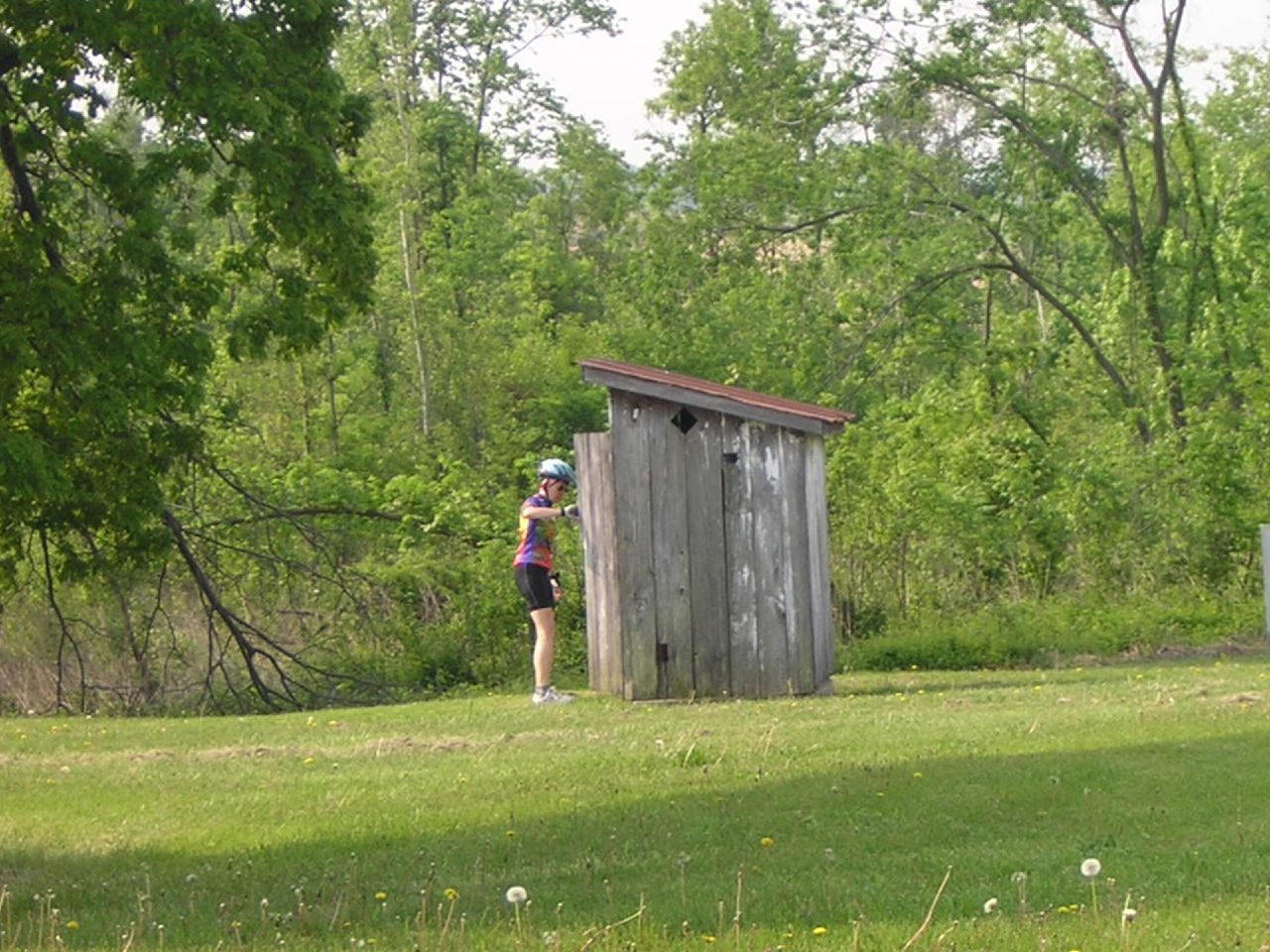 the person is taking a break from skiing to look at a outhouse