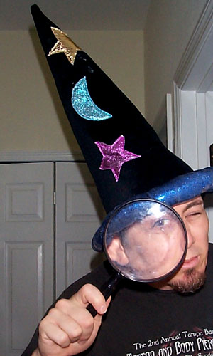 a man with a witch hat on has his hand on a magnifying glass