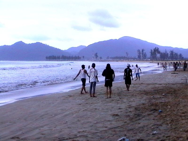 several people walking down a beach with waves coming in