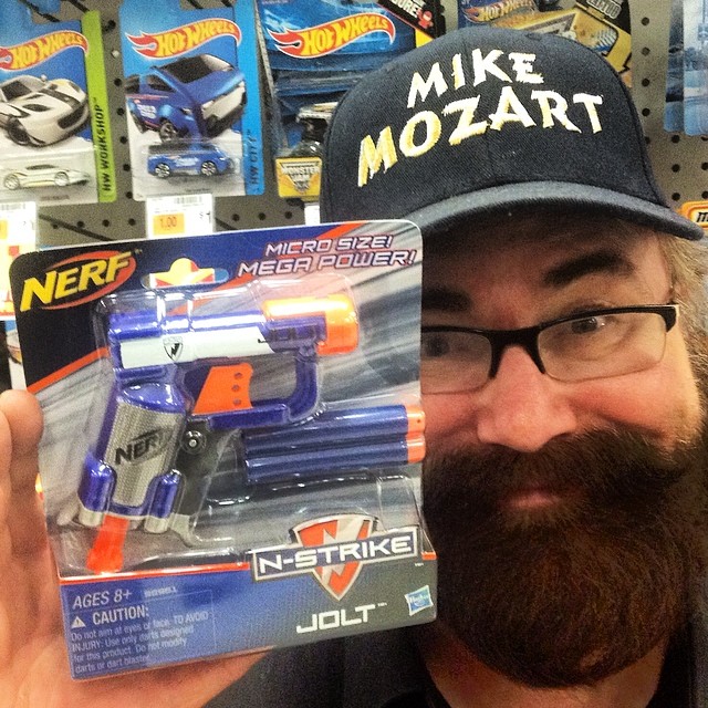 a man in a hat holding up a nerf toy gun