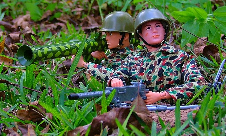 two toy army men aiming missiles from behind on the ground