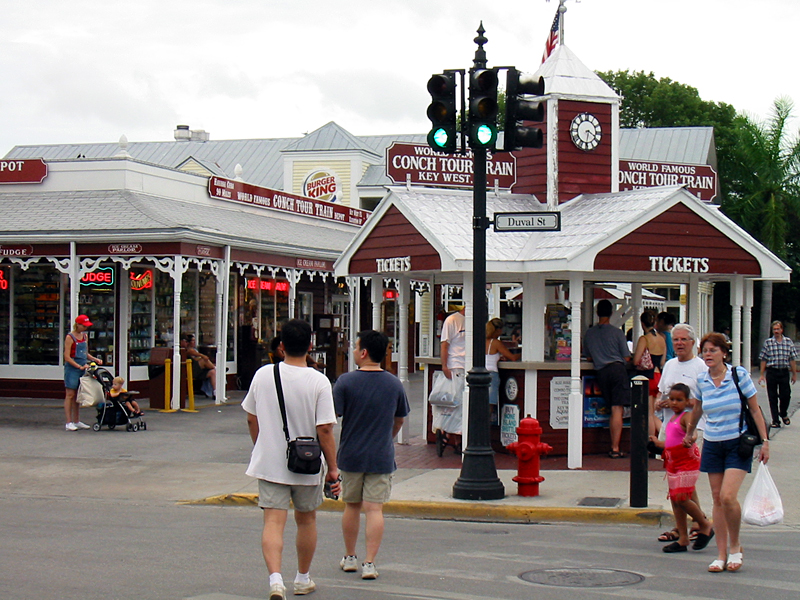 people walk through an intersection in front of stores