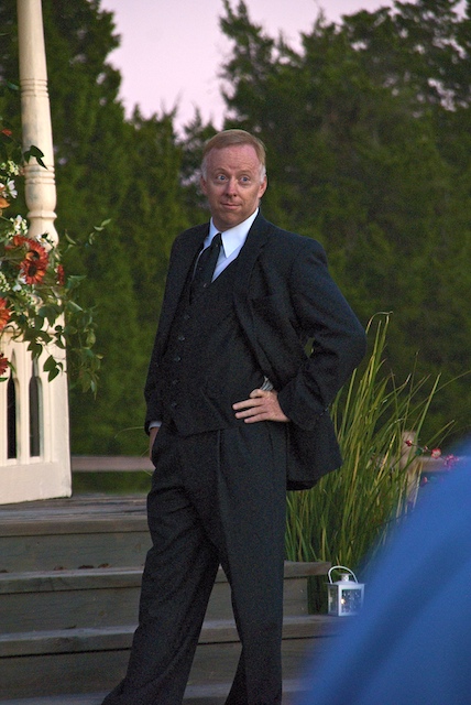 a man in a black suit with his hands on hips