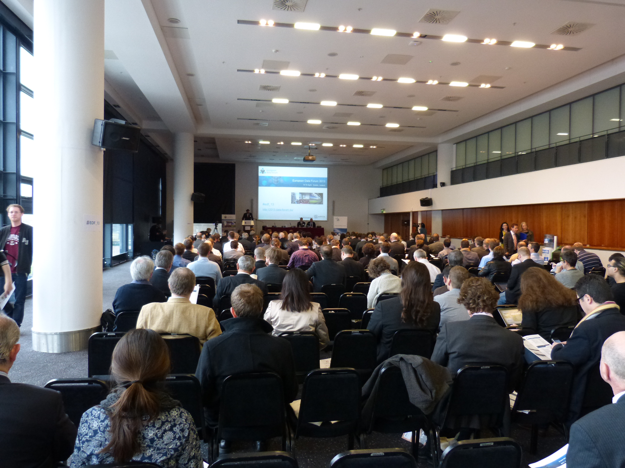 many people are sitting at tables in an auditorium