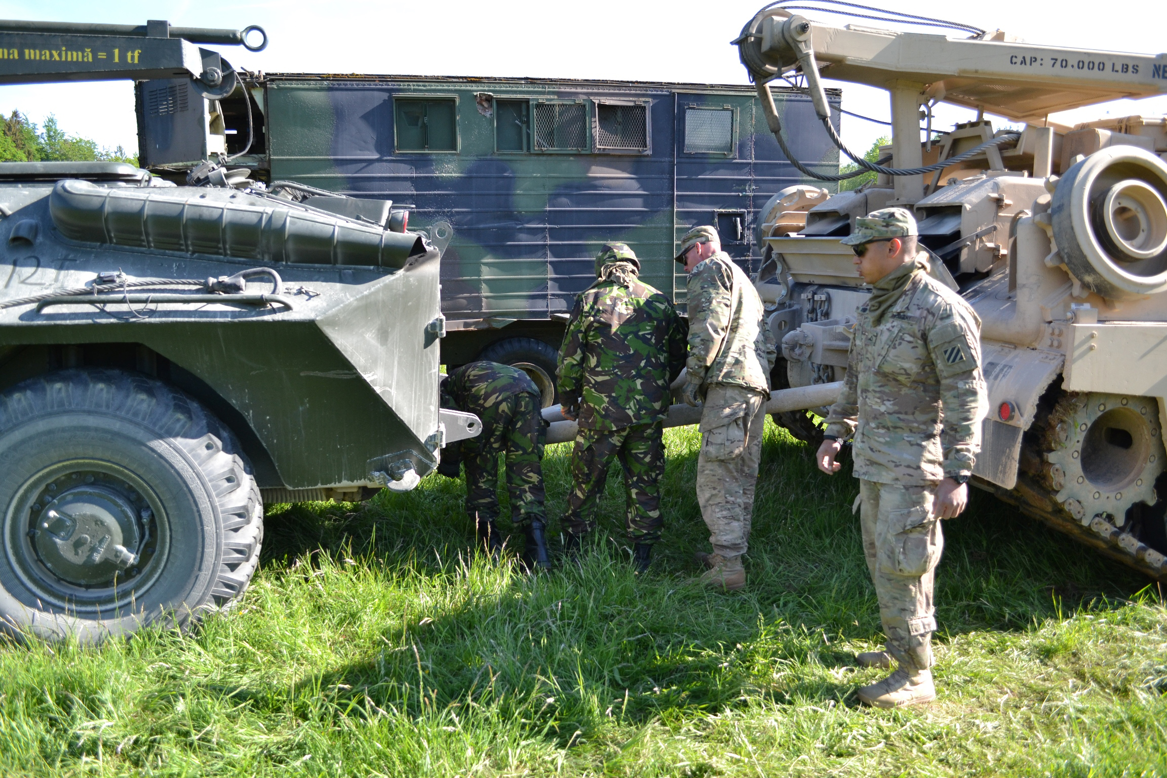 three military men in uniform standing near a military vehicle