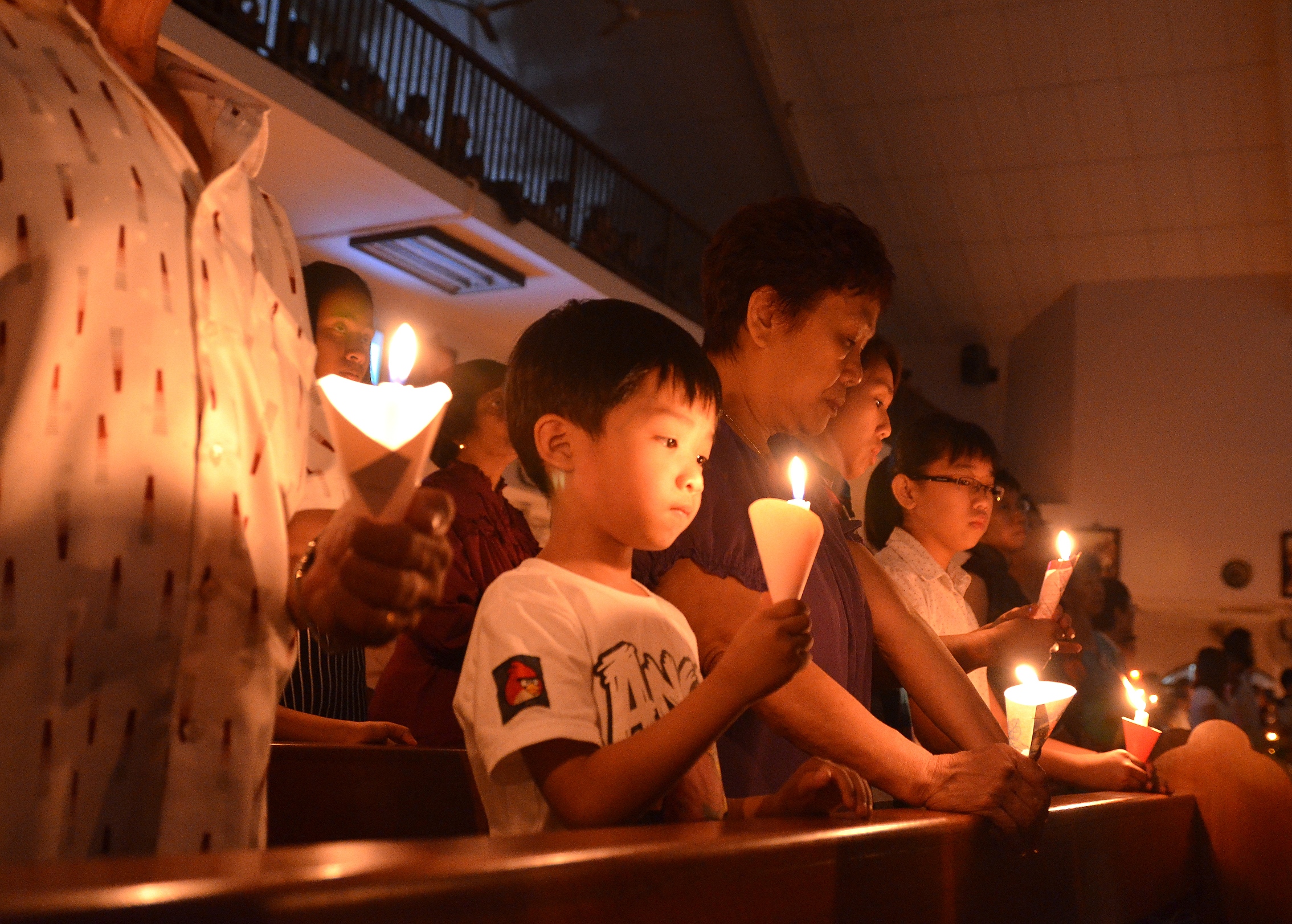 a bunch of people hold candles while looking down on them