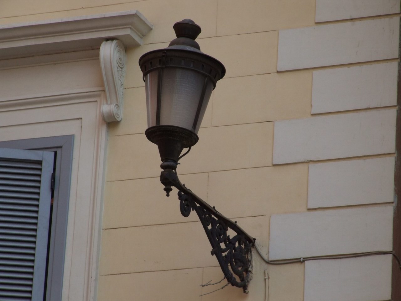 an old fashioned street lamp attached to a building