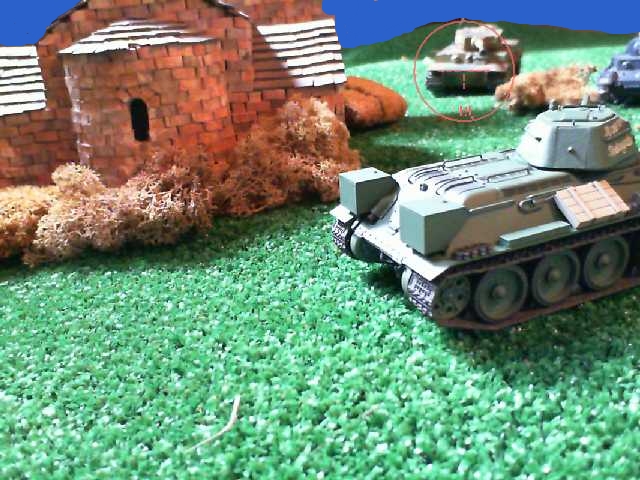 some toy cars and tanks sitting on grass