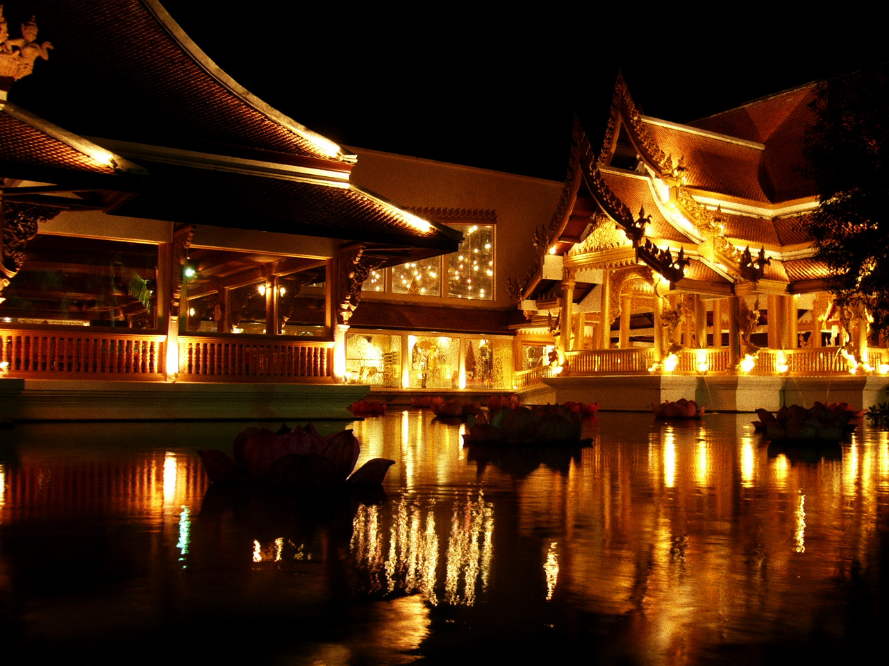 a building sitting on top of a lake in front of a tall bridge