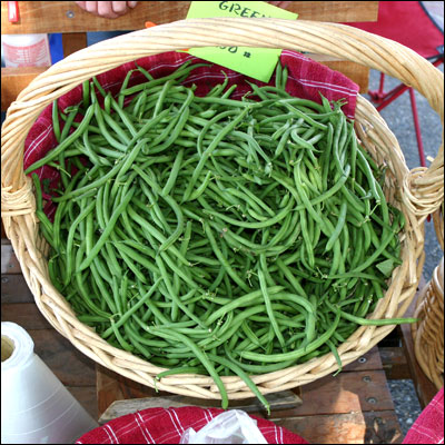 a wooden basket holding green beans with labels