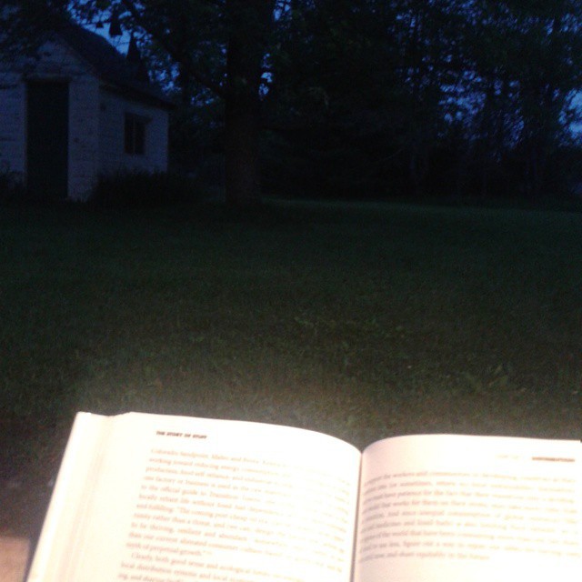 an open book sitting in the grass next to trees