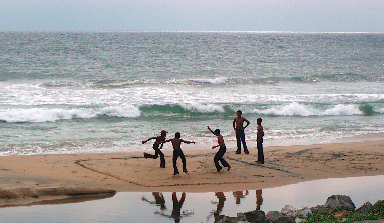 a group of s standing on top of a sandy beach