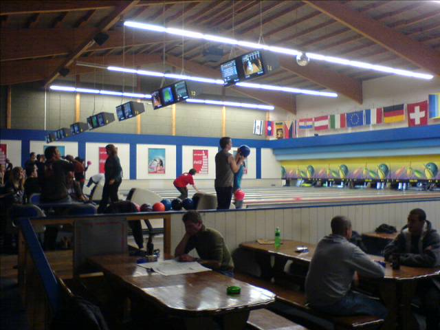 several people are sitting at tables in a bowling alley