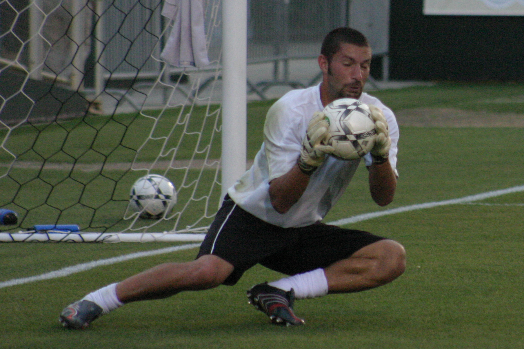 there is a male soccer player reaching out to save the ball