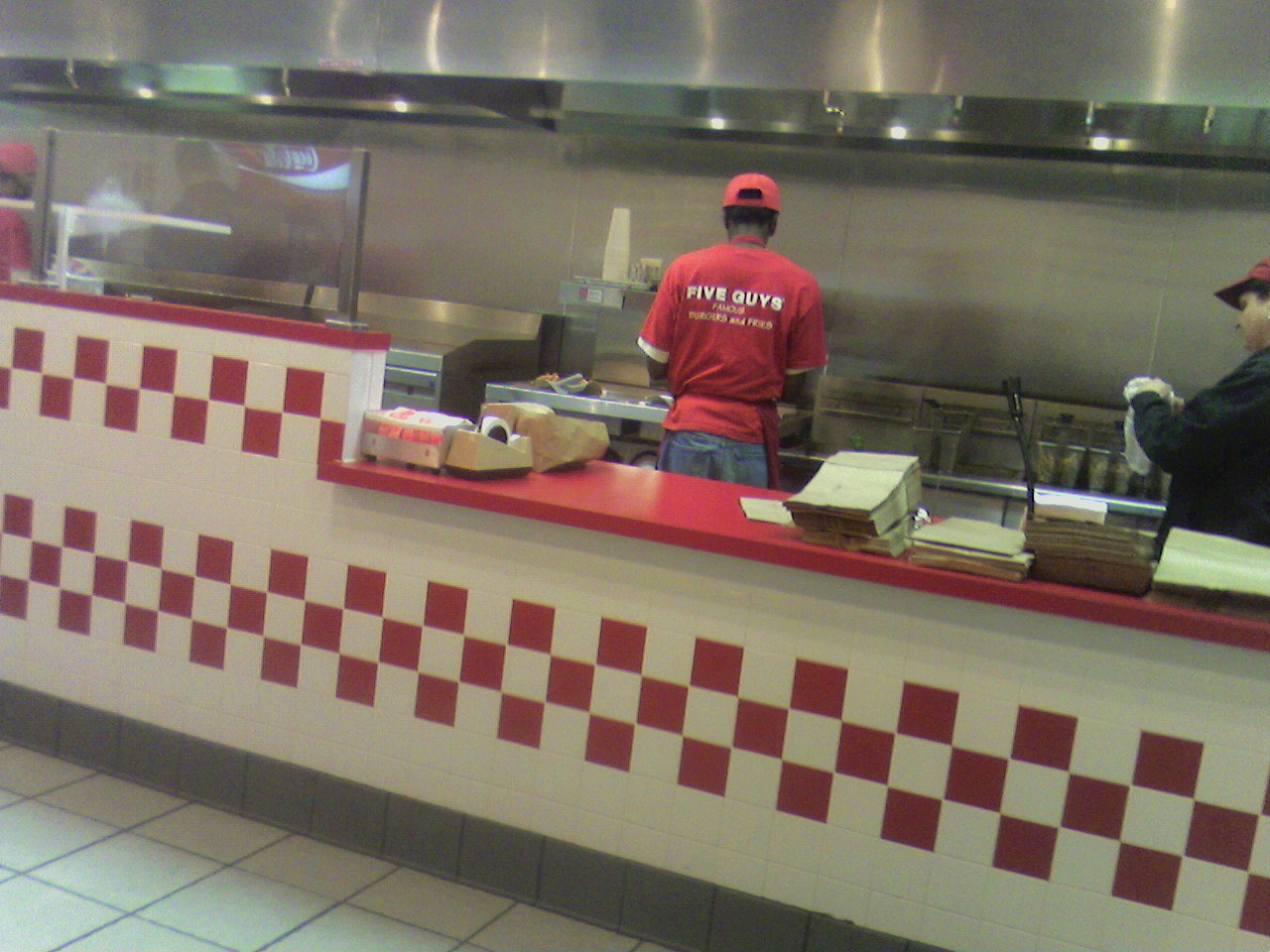 two men standing behind a counter at a restaurant