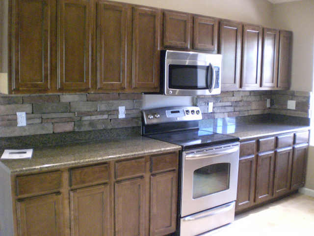 a microwave and oven are in a kitchen with granite counters