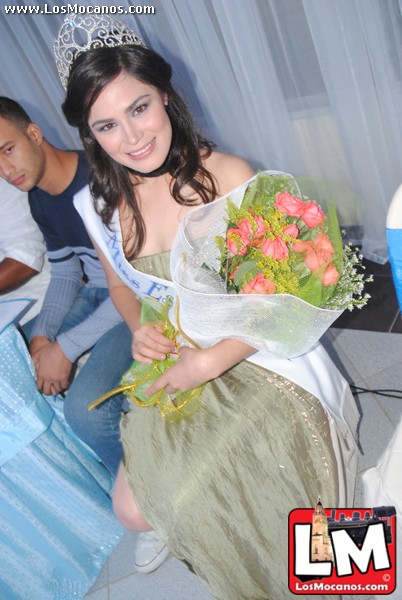 a woman in a dress holding flowers near two men
