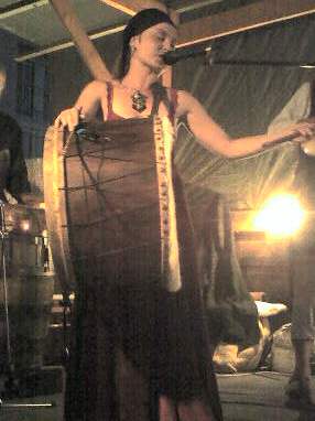 a woman in a long dress sings into a microphone