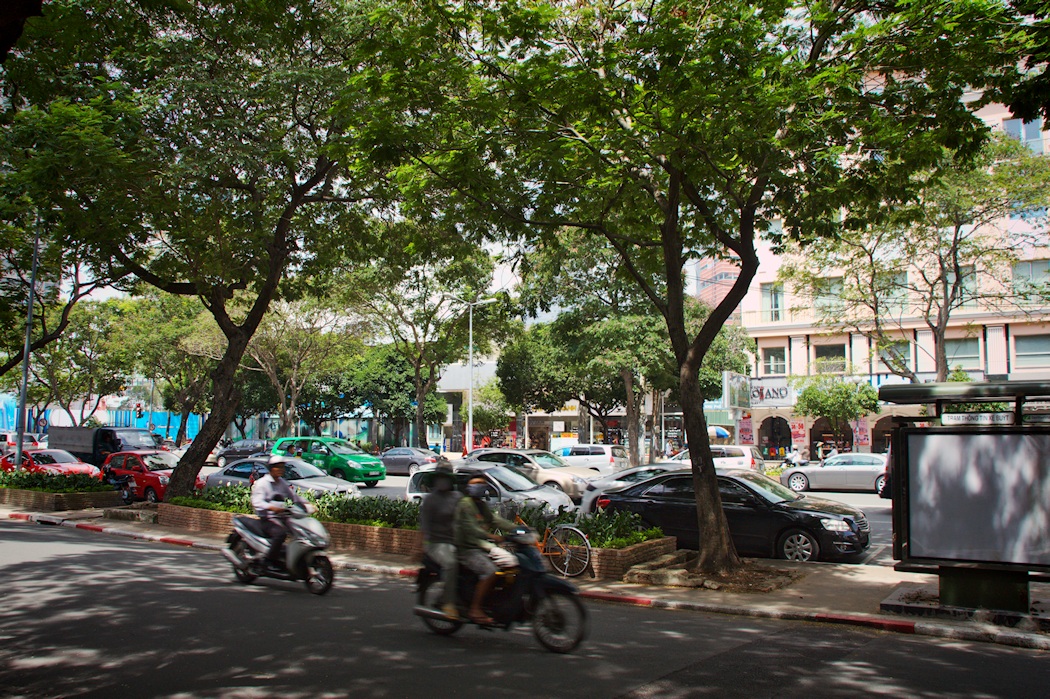 a couple of people riding on the back of mopeds down a street