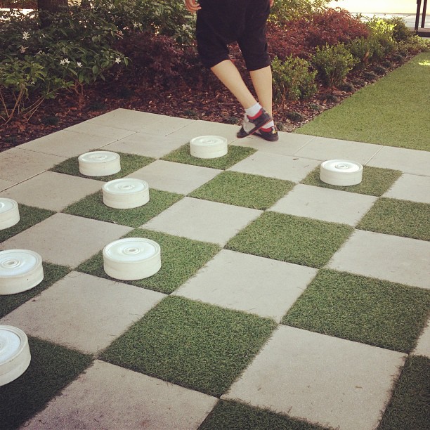 an outdoor game of checkers made out of plastic barrels