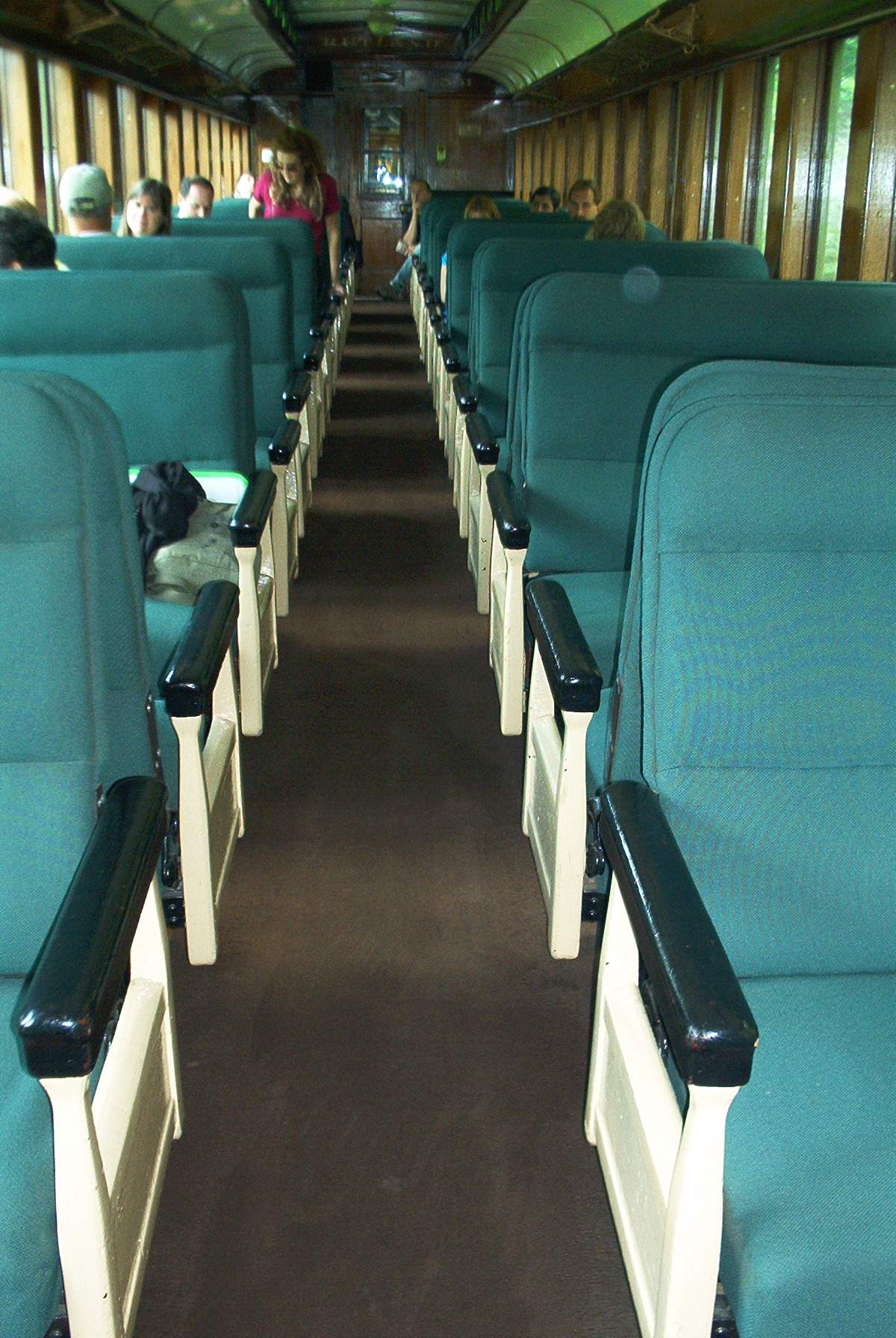 a large green bus with several seats and people sitting in it