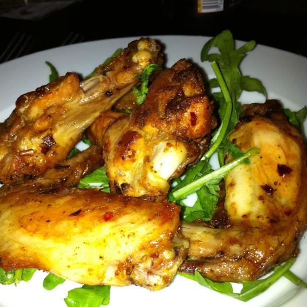 a plate has several chicken wings with greens