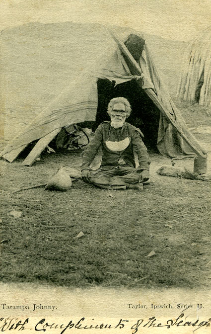 a young man squats in front of a very large tent