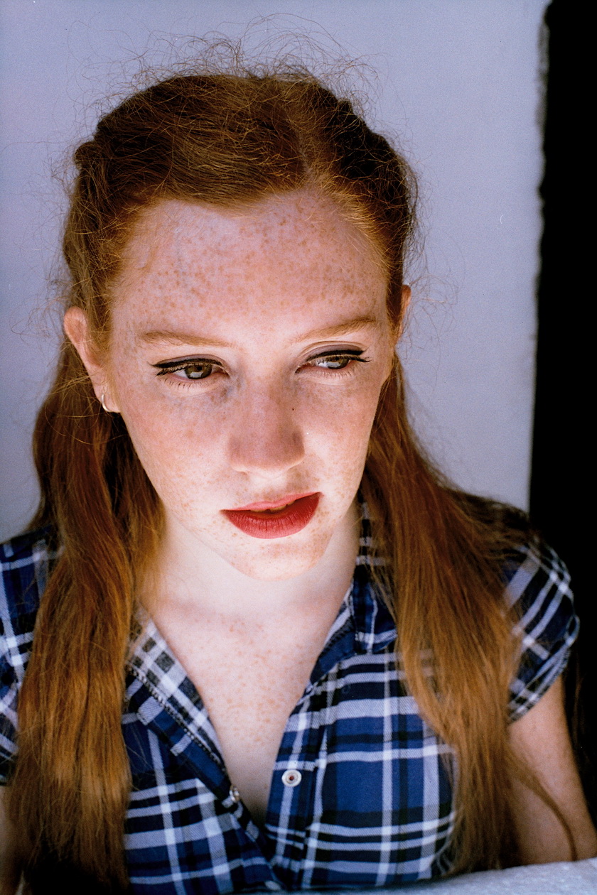 a woman with freckled red hair looks to the side