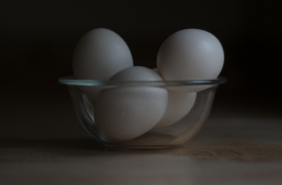 three white eggs are in a bowl on a table