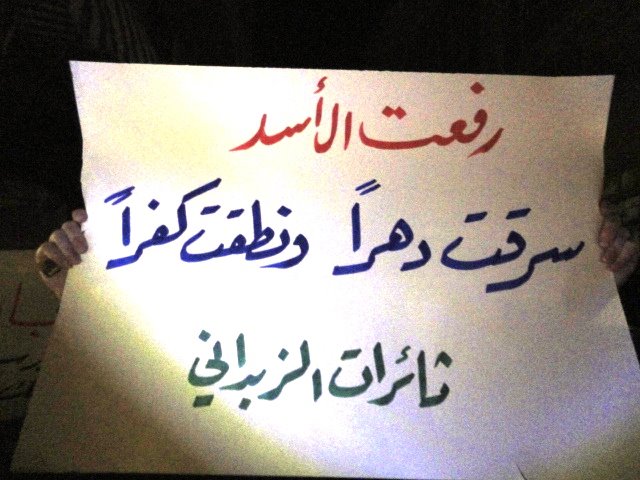 a man holds a sign that is written in an arabic language