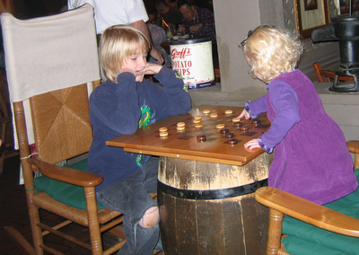 two small children playing a game on an old barrel