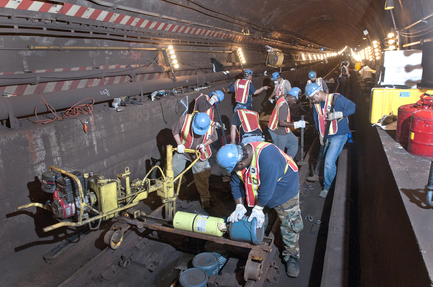 workers wearing hard hats and safety vests work inside a train