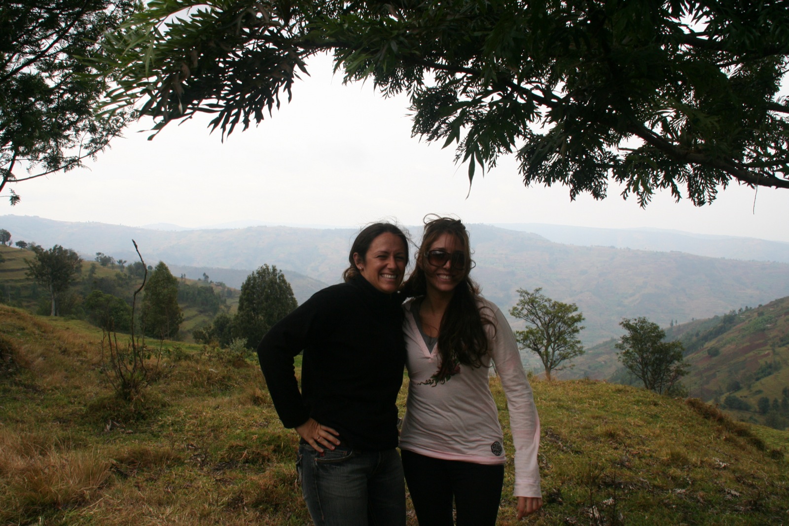 two young people stand smiling in the mountains