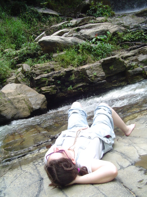 a lady laying on the rocks near a river
