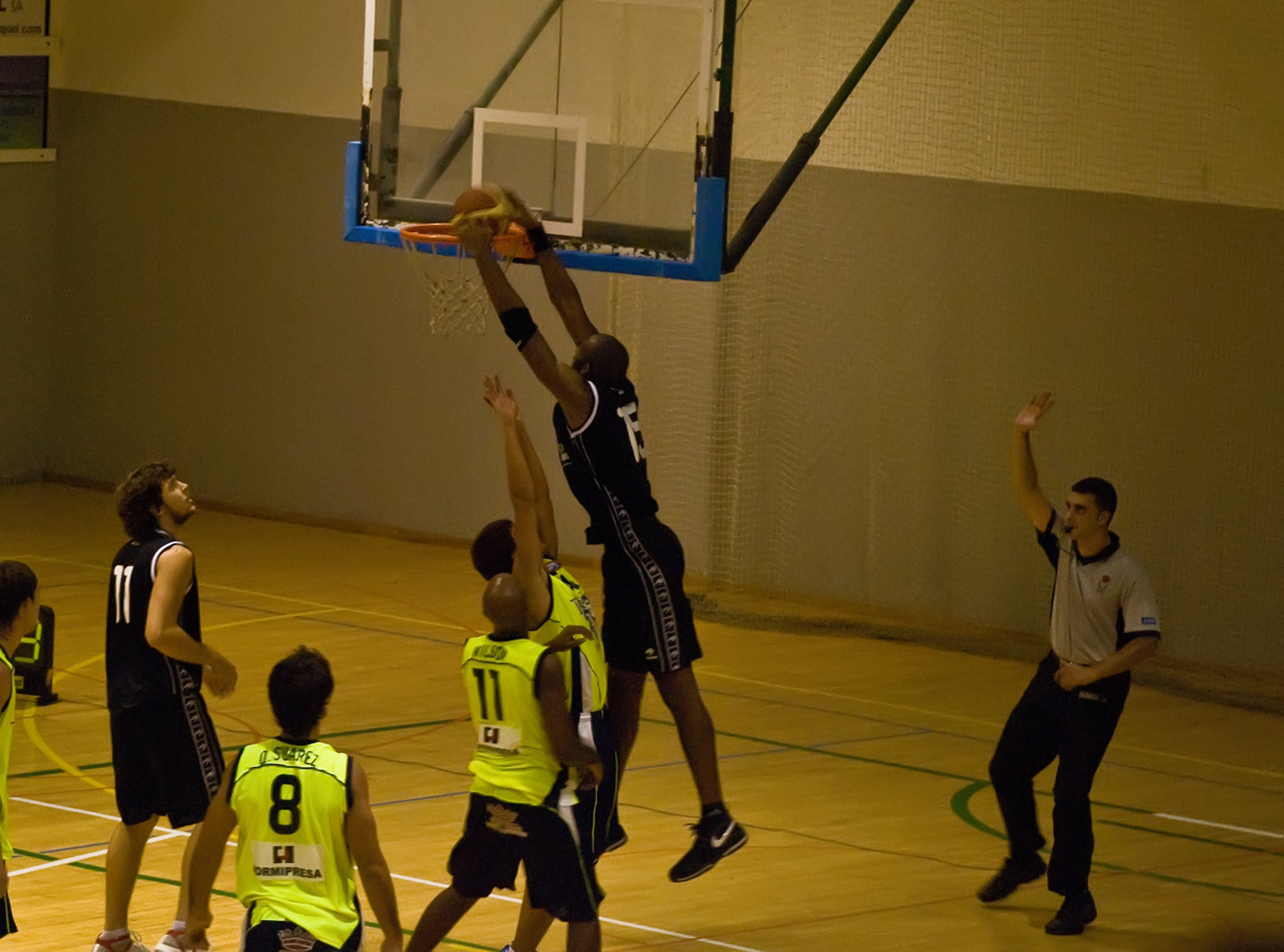 a basketball player tries to block the ball from going into the net