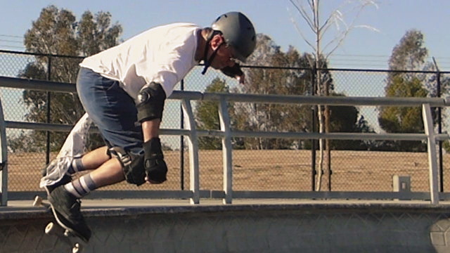 man on skateboard doing trick with fence in background