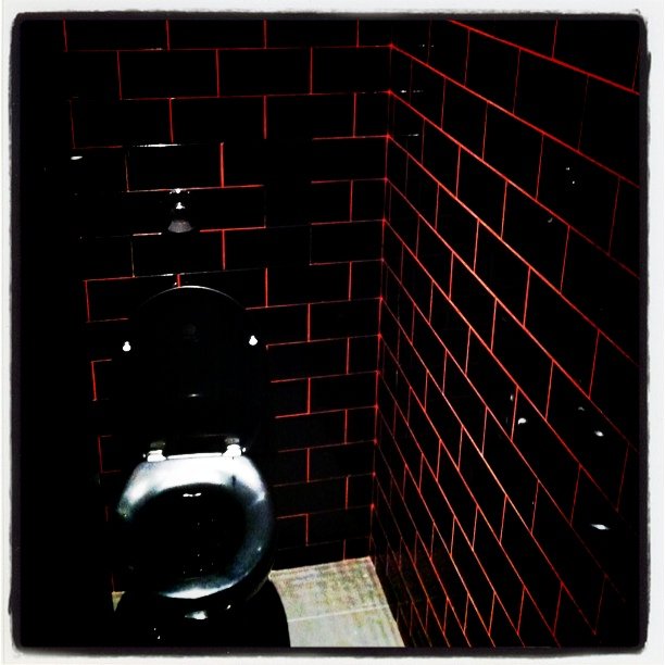 a small restroom with a toilet, and some red lights on