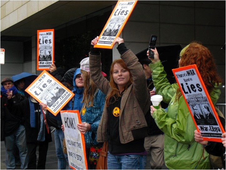 women protesting outside of a building holding signs