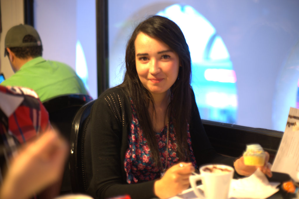 girl sitting at table with food and drink smiling