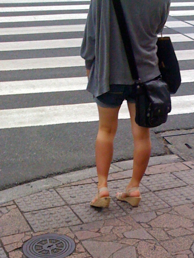 the woman with sandals is waiting at the crosswalk