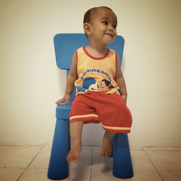 a child sitting on a blue chair smiling