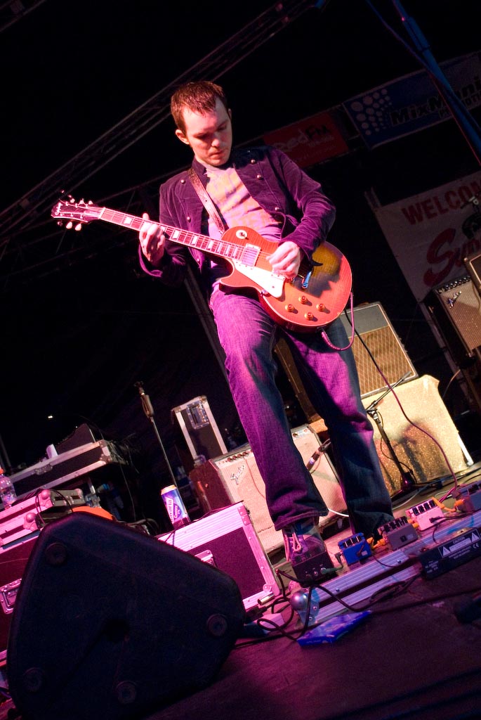 a male in a purple shirt playing a red guitar