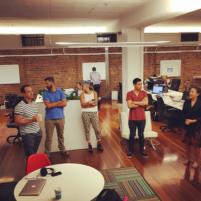 several people standing in a large office with chairs