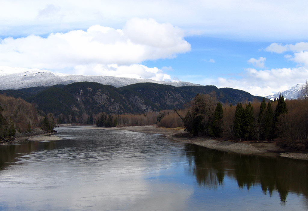 a view of a lake surrounded by snow and trees