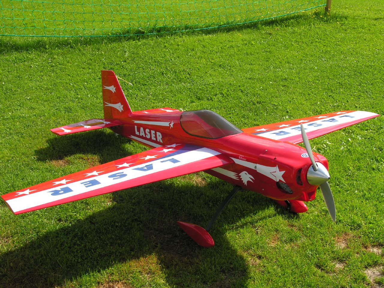 a model airplane sits in the grass near a soccer net