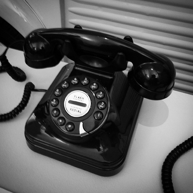a black and white phone on a desk with a window