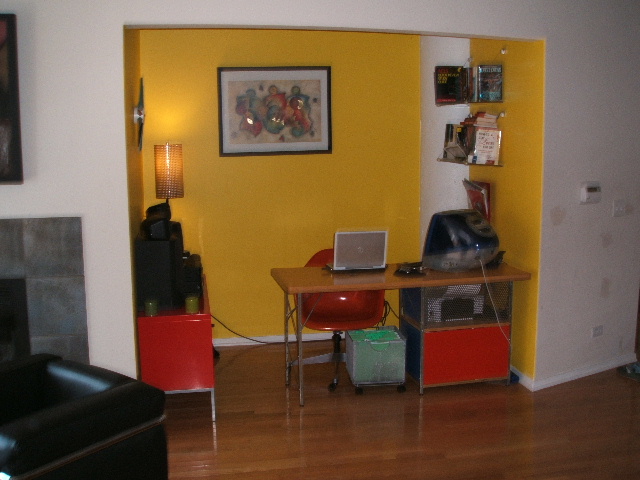 a wooden floor in front of a desk and yellow wall