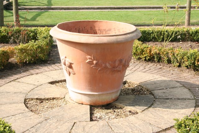 a large brown pot sitting on top of a stone walkway
