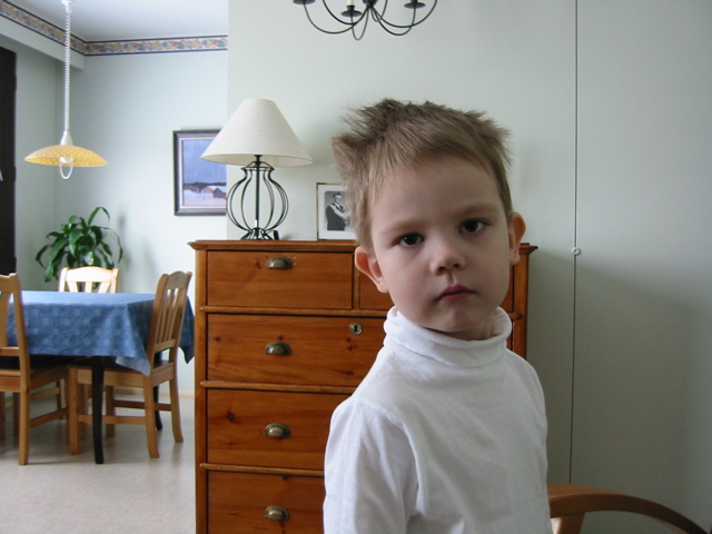 a little boy standing in front of a dresser