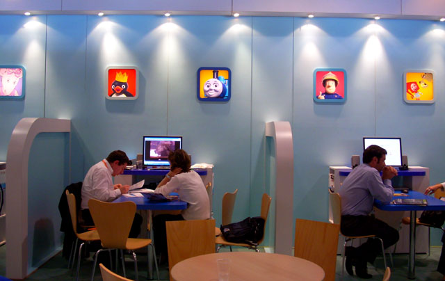 three men at tables and two women at computers